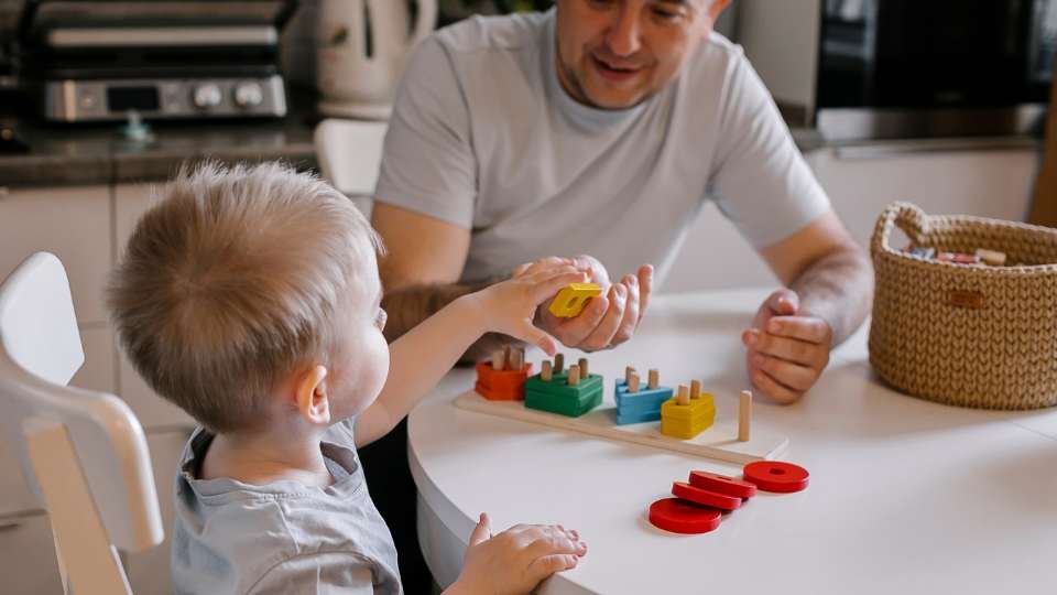 Man, child, playing at table.